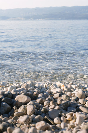 Close-up view of the pebbles and waves at the beach on an sunny day. Close-up shot