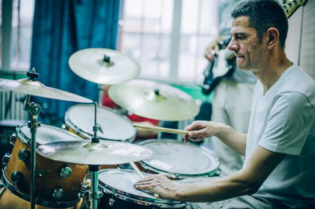 Behind the scene. Male drummer artist musician playing the drums with drumsticks in messy recording...