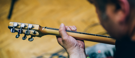 Behind the scene. Male guitarist artist musician practice playing guitar in messy recording music studio. Live musicの写真素材