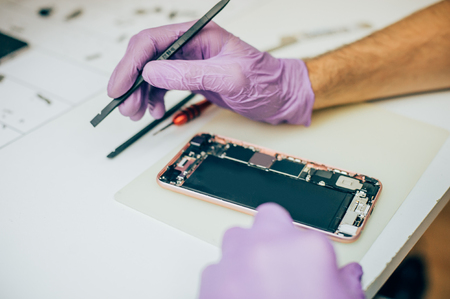 Technician repair faulty mobile phone in electronic smartphone technology service. Cellphone technology device maintenance engineerの写真素材