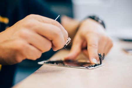 Technician repair faulty mobile phone in electronic smartphone technology service. Cellphone technology device maintenance engineerの写真素材