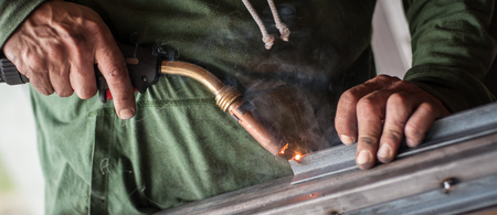 Industrial worker welding the steel structure in the workshop. Flies of spark from hot metalの写真素材