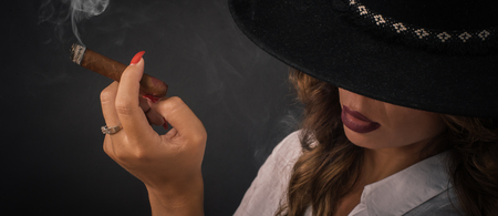 Portrait of sexy elegant lady woman with hat smoking cigar. Fashion glamour style. Studio shootの写真素材