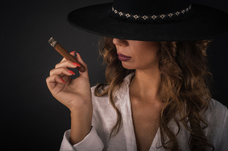 Portrait of sexy elegant lady woman with hat smoking cigar. Fashion glamour style. Studio shootの写真素材