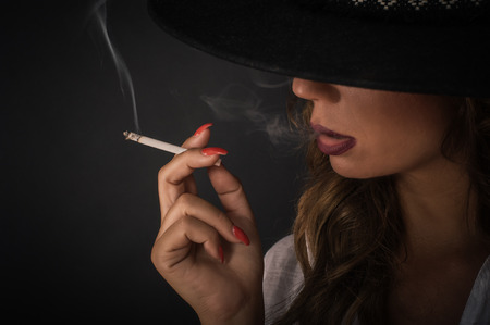 Portrait of sexy elegant lady woman with hat smoking cigarette. Fashion glamour style. Studio shootの写真素材