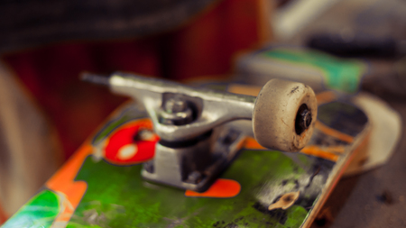 Young man in carpentry workshop fixing wheel on his skateboard. Close upの写真素材