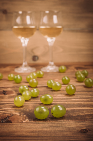 Two glasses of white wine and grapes on wooden table. Close upの写真素材