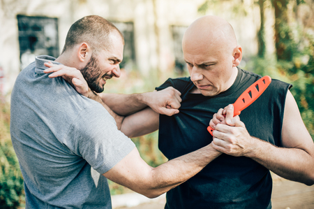Kapap instructor demonstrates martial arts self defense disarming technique against threat and knife attack. Weapon retention and disarm training. Demonstration with plastic knifeの写真素材