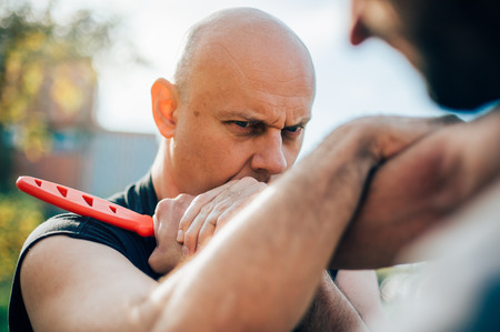 Kapap instructor demonstrates martial arts self defense disarming technique against threat and knife attack.の写真素材