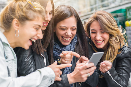 Happy four friends walking on the street and using cellphones. Internet and social media