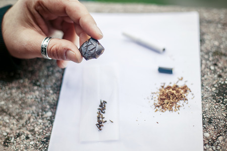 Hashish set. Man preparing hashish joint rolling marijuana cigarette for smoking. Close upの写真素材