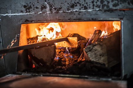 Firewood wood burn in retro rusty rural metal stove. Close upの写真素材
