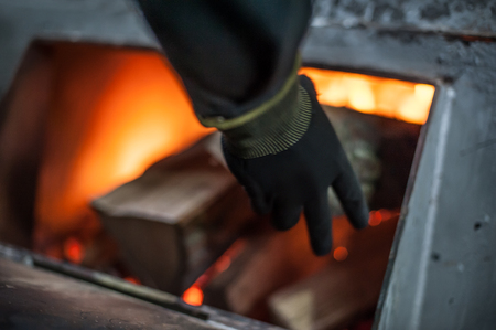 Man putting log onto wood burning stove. Close upの写真素材