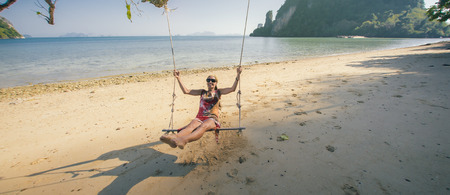 Young happy woman enjoying and relaxing at swing at tropical ocean beach. Koh Phi Phi, Thailandの写真素材