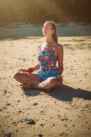 Fit woman relaxing and practicing yoga outdoors by the sea. Relax and meditate conceptの写真素材