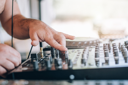 Close up of Disc Jockey hands plays music with DJ CD player and mixer on a private summer day partyの写真素材