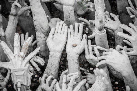 WAT RONG KHUN - WHITE TEMPLE, CHIANG RAI THAILAND - CIRCA MAY 2018. The sculpture of beggar hands collect metal coin money - the sculpture of hundreds outreaching hands that symbolize unrestrained desire.のeditorial素材