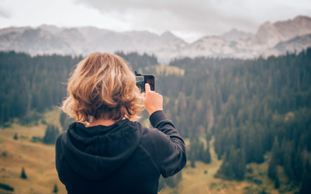 Hiking woman taking panoramic picture of summer mountain landscape. Selfie photo stick. Zabljak...
