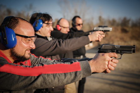 Group of people practice gun shoot on target on outdoor shooting range. Civilian team weapons trainingの写真素材