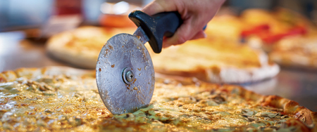 Cutting margarita pizza on slices with special knife. Tasty fast food italian traditionalの写真素材