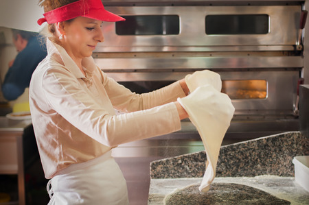 Professional chefs stretch and rolling out dough for pizza. Woman kneading raw doughの写真素材