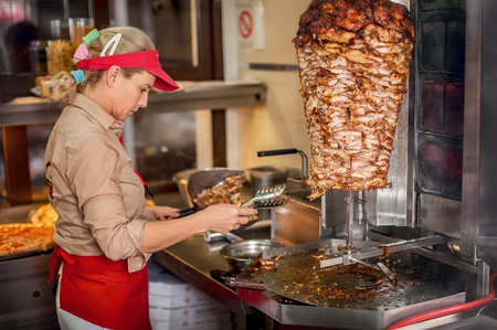 Chef preparing roasted sliced gyros meat in fast food restaurant. Traditional greek fast foodの写真素材