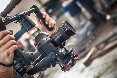 Videographer using stadicam, making video of machine at factory. Close up