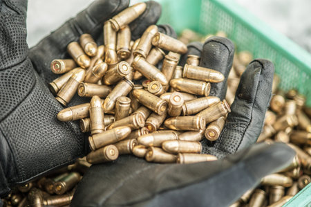 Top detail macro view of hands in glove with large group of gun bullets