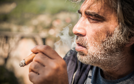 Portrait of bearded caucasian man smoking a cigar. Close upの写真素材