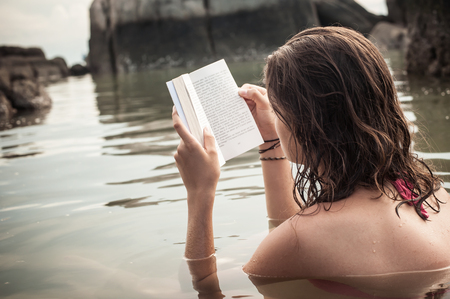 Young woman read book during beach vacation. Summer holiday tripの写真素材