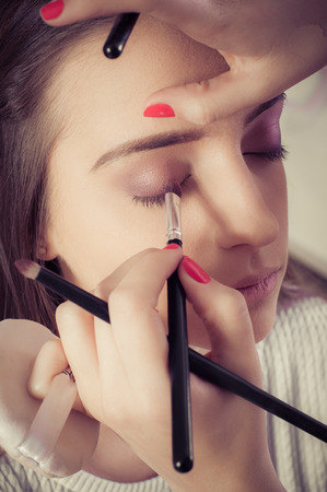 Woman face makeup. Closeup of hands applying eyeshadow powder on female facial skinの写真素材