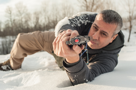 Instructor demonstrate body position of combat gun shooting at winter deep snow. Advanced fighting tactical shooting courses on outdoor shooting rangeの写真素材