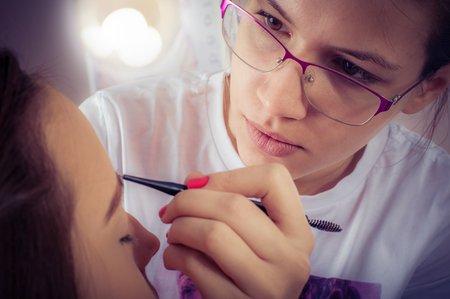 Professional artist is making beauty makeup to young girl in beauty salonの写真素材