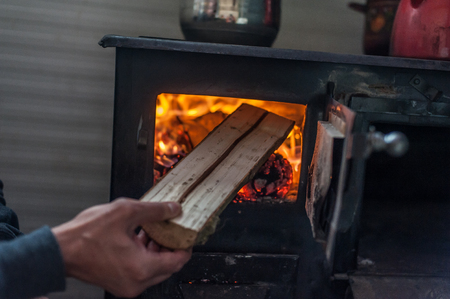 Man putting log to wood burning stove. Close upの写真素材