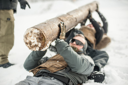 Instructor and army soldiers in complete equipment have hard training with huge chump wood on extreme cold and snow winter dayの写真素材