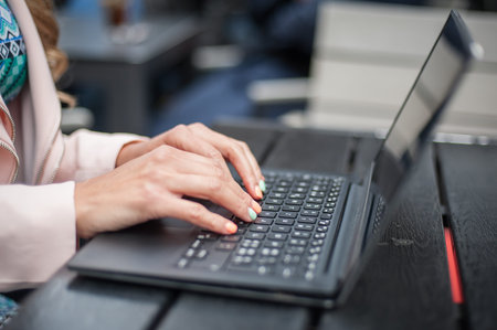 Close up of woman hand, blogger freelancer in outdoor cafe with computer laptop
