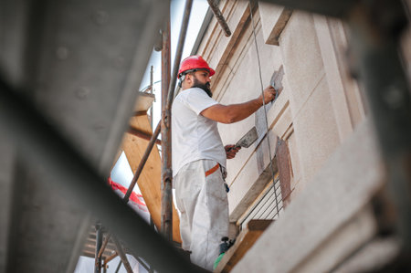 Man worker standing on scaffolding, perform work on the restoration of the facade of the old...