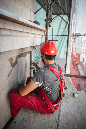 Man worker standing on scaffolding, perform work on the restoration of the facade of the old...