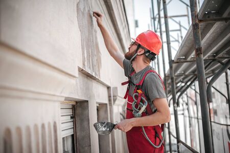 Construction mason worker plastering old building wall using cement plaster mix of cement and sand at the construction siteの写真素材