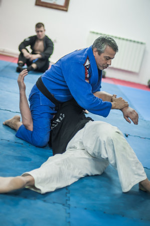 BELGRADE, SERBIA - 13. OCTOBER 2019. Sensei master Avi Nardia in traditional kimono, demonstrate BJJ Brazilian jiu-jitsu ground control and finish technique to his students on Kapap Krav Maga seminarのeditorial素材