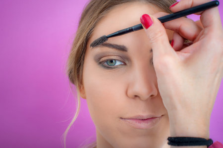Makeup professional artist applying black mascara on lashes of model eye. Woman beauty model. Close...