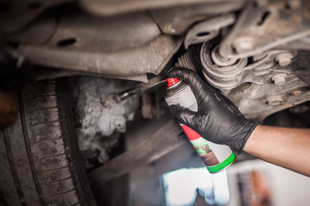 Car master mechanic repairer lubricates the screws with a machine parts cleaner oil dirt grease...