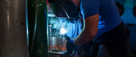 Auto mechanic working with welding mask cooking metal on automatic welding machine for repairing...