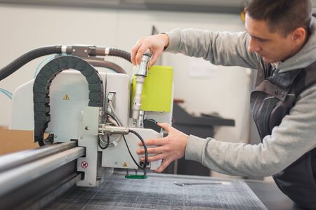 Electrical engineer repairs a knife cutting head on large CNC computer numerical control printing and cutting machineの写真素材