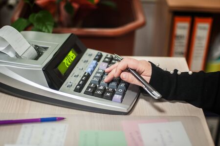 Close-up of female accountant hands, calculates and research the financial data position of the company and planning the economy financial profit or loss of bank accountsの写真素材