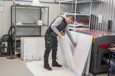 Worker printmaker technician operator works in large digital printing press hall and printshop...