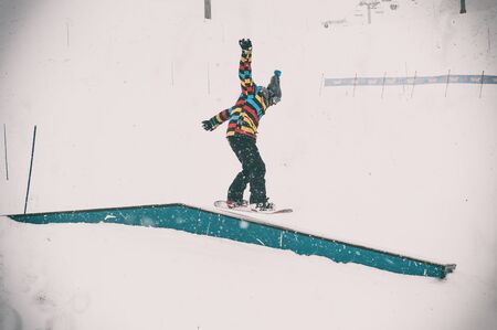 Freerider snowboarder doing basic snowboard rails trick in freestyle snowpark. Winter mountain season の写真素材