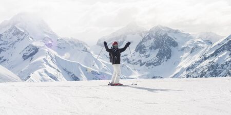 Happy and positive female skier on the top of the mountain raise up hand with enjoy and happiness and enjoy in beautiful snowy alps mountain range. Winter season sport and recreation travel conceptの写真素材
