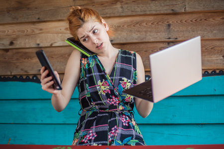 Young crazy hipster talking on the mobile smart phone, using tablet and looking on laptop. Internet...