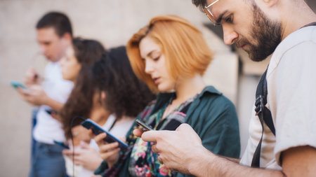Group of friends using smartphones together. Young people addiction to new technology trends. Youth,...